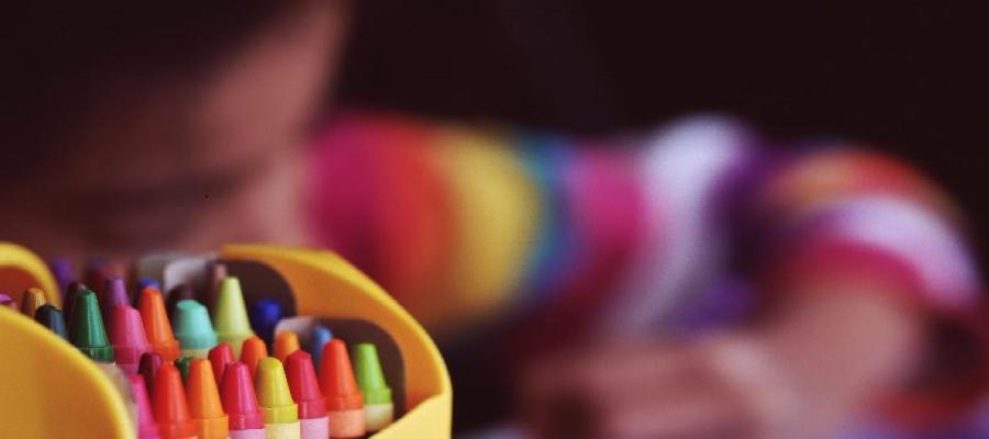 Colorful Crayons and a Girl Painting in the background