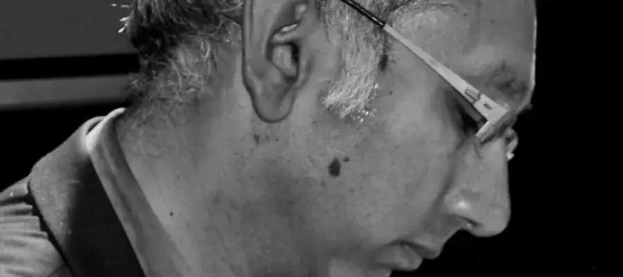 Black and white image of Kenan Malik in profile. He has greying hair and wear spectacles.