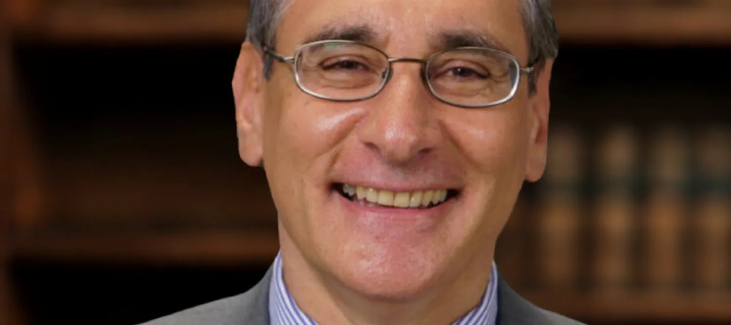 Professor Angelos Chaniotis has short grey hair and wears metal frame glasses. He smiles broadly at the camera.