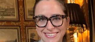 Chiara Bonacchi - she has dark hair tied back, thickly rimmed glasses and smiles at the camera