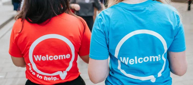The back of two girls wearing t-shirts bearing the legend 'Welcome'