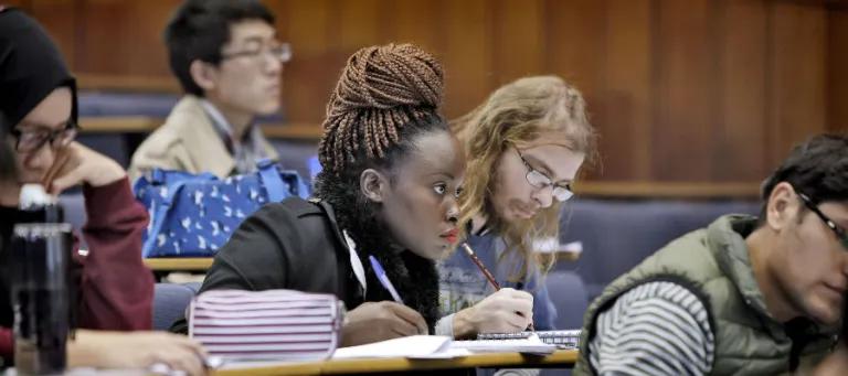A group of students taking notes in a lecture theatre.
