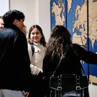 A group of students stand before the map discussing it