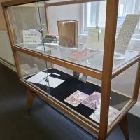 A wood and glass display case containing books and letters