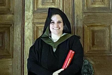 Anna wears academic robes on her graduation day