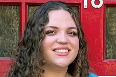 Ariella has long wavy hair and smiles at the camera
