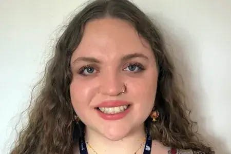 Ariella has long wavy hair and smiles at the camera