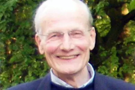 Alan Day has short white hair and wears framed glasses. He smiles into the camera.