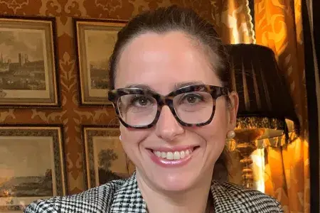 Chiara Bonacchi - she has dark hair tied back, thickly rimmed glasses and smiles at the camera