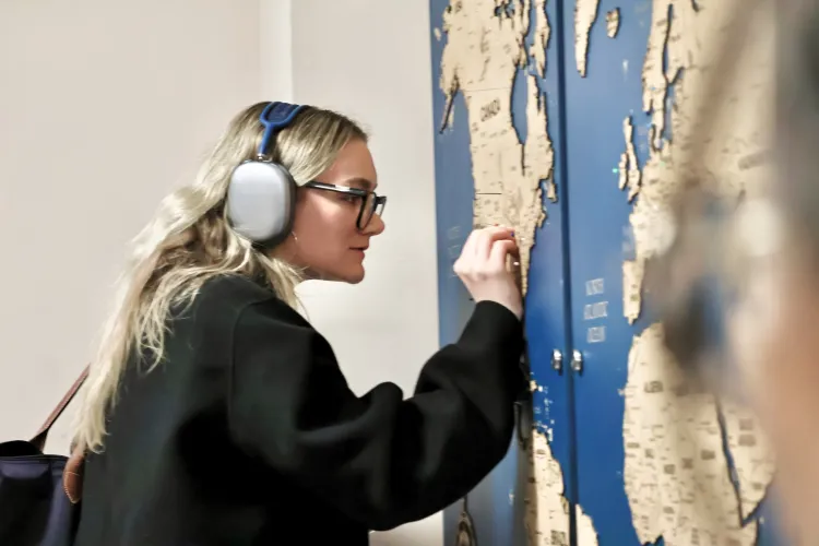 A female student with long blonde hair places a pin in the map