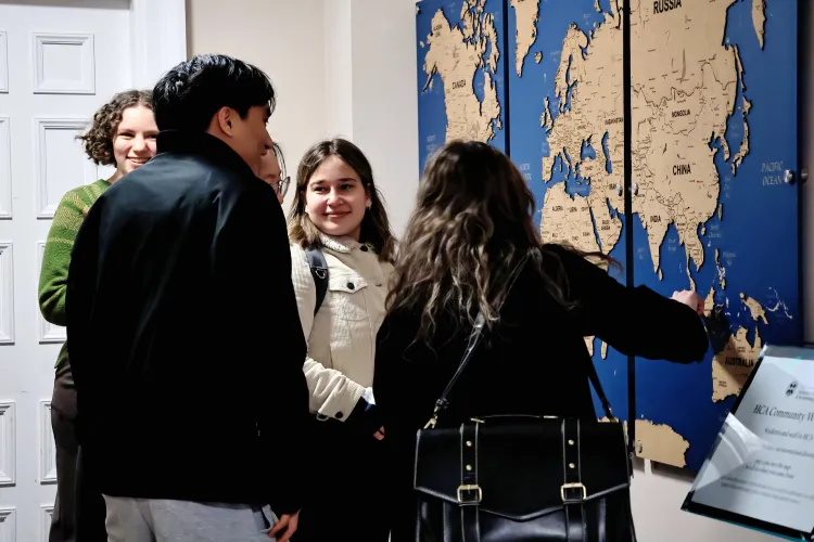 A group of students stand before the map discussing it