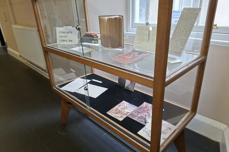 A wood and glass display case containing books and letters