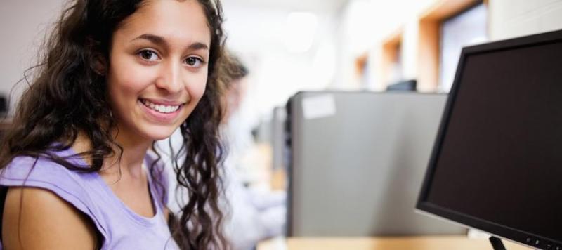 Female student smiling in front of a computer