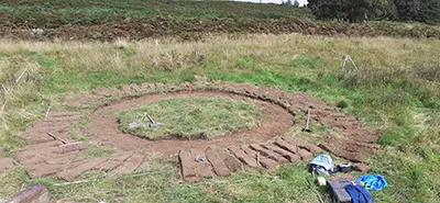 HCA beginning to biuld a turf wall, a circle of turf has been cut from the ground