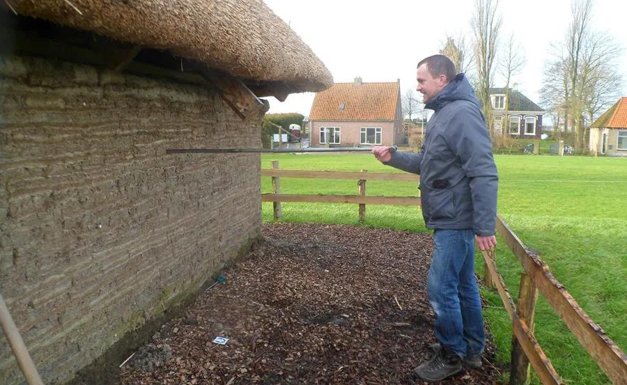 Image showing researcher taking samples from the wall of a turf house
