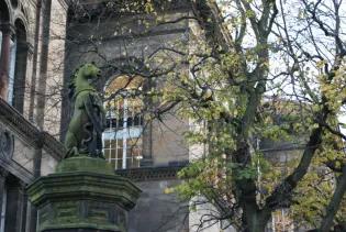 A stone unicorn stands atop a pillar beside the Old Medical School and trees