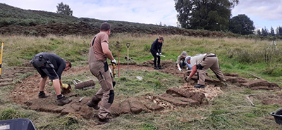 HCA Cutting the footprint of the circular turf enclosure at Comrie Croft, Perthshire, modelled on a prehistoric roundhouse in the area.